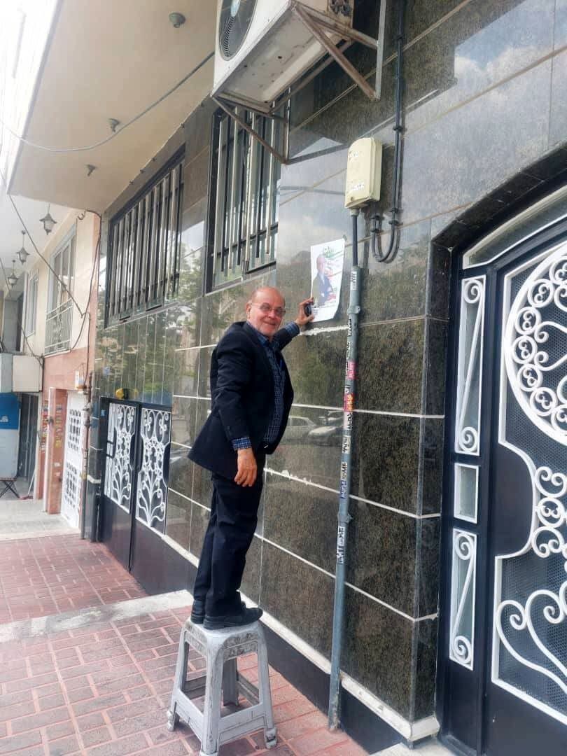 عکسی از استاد دانشگاه شریف هنگام چسباندن پوستر انتخاباتی